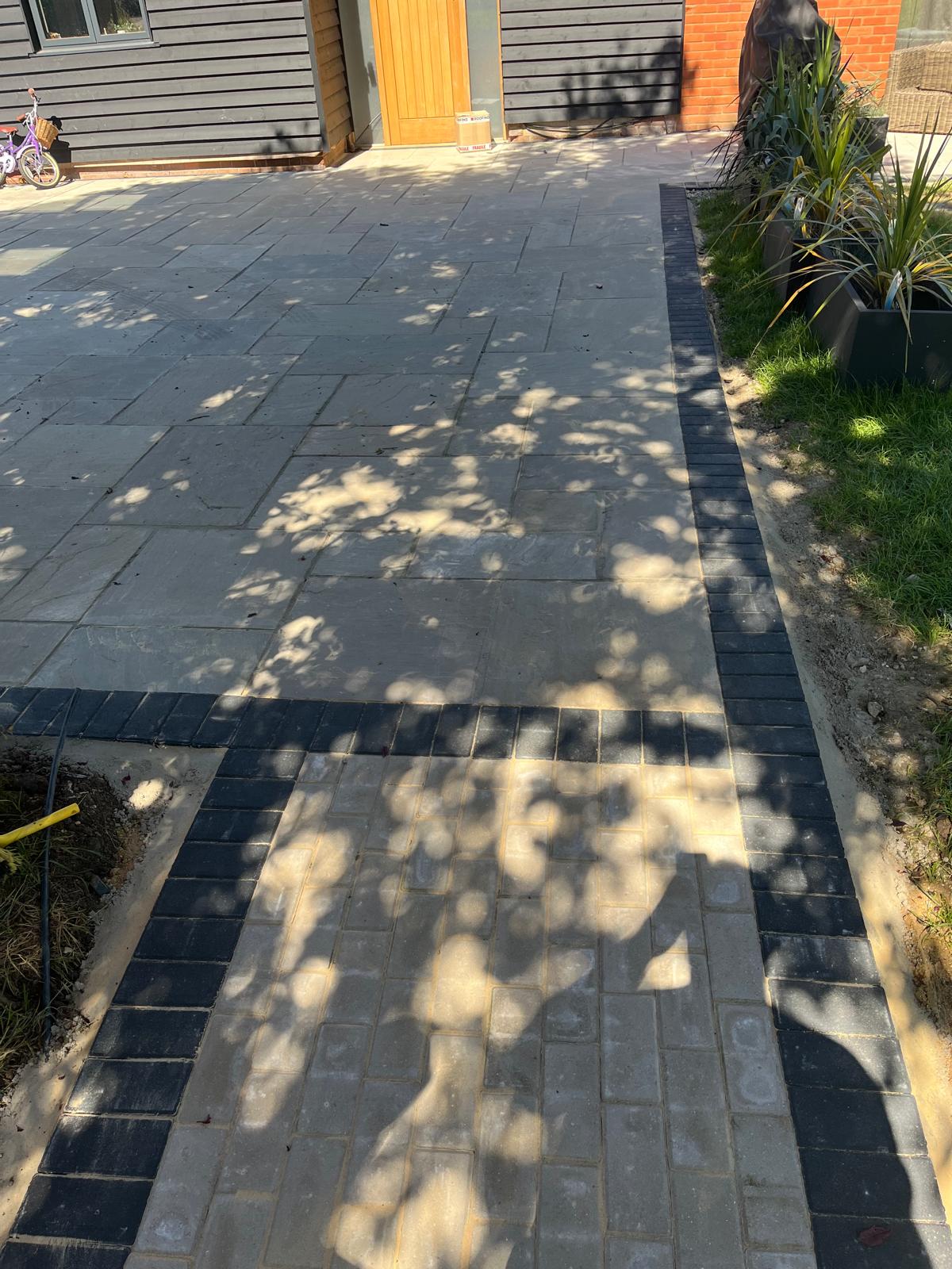 Dark garden slabs beside planted bed