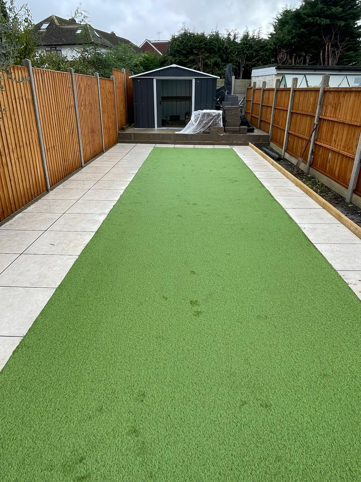 Long artificial lawn with pale paving border